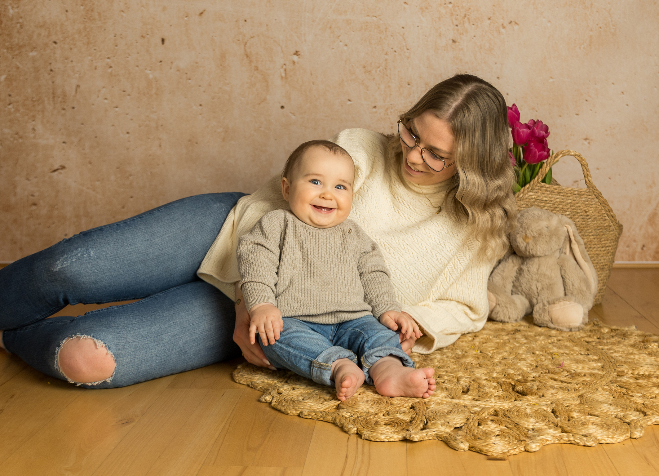 Mutter und Baby sitzen auf dem Boden und lachen glücklich in die Kamera