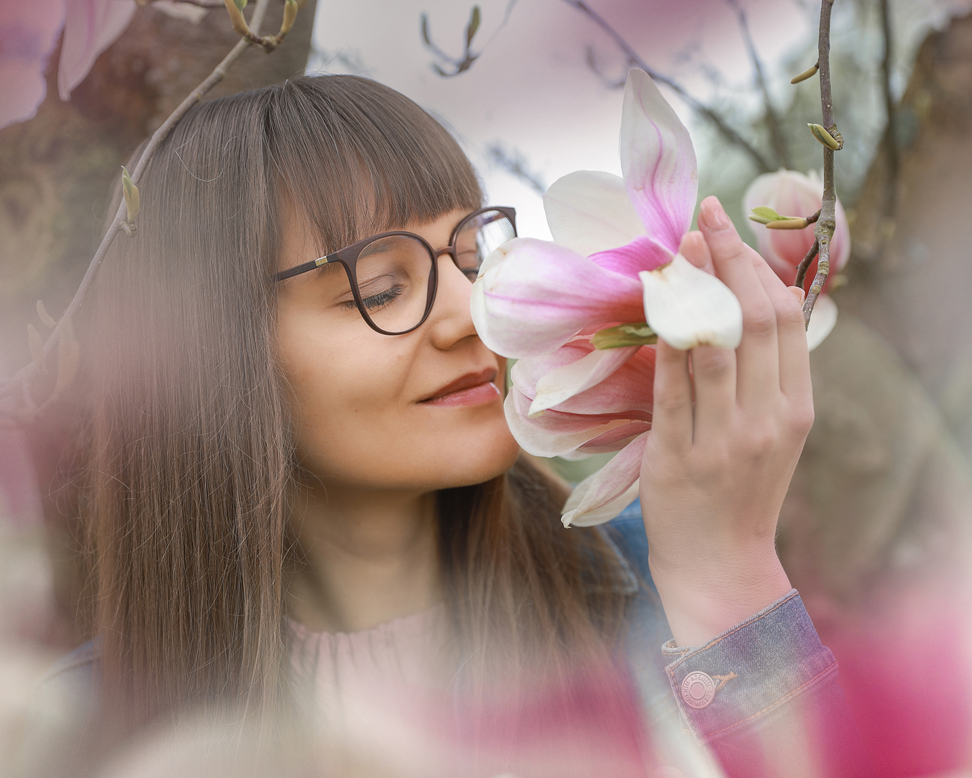 Frauenportrait-dorisdörfler-lichtblick-onlocation-magnolienbaum-frühling-pegnitz Junge Frau mit Brille riecht an einer Magnolienblüte, zartes Portrait im Frühling.