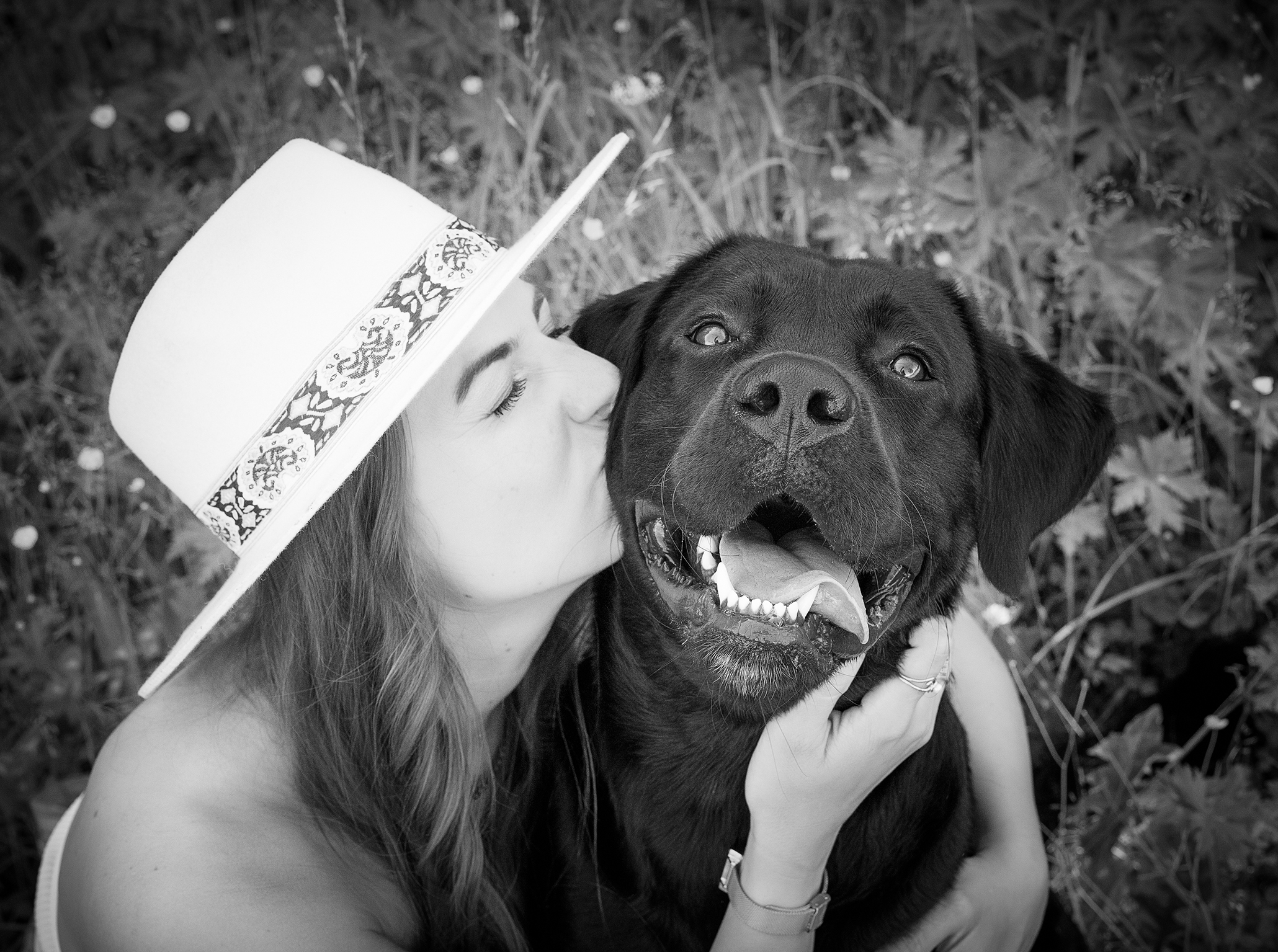 Frühling-2026-hundefotos-doris-dörfler-fotostudio-lichtblick-pegnitz Schwarz weiß Portrait einer Frau mit ihrem Hund, sie küsst ihn liebevoll, der Hund schaut fröhlich in die Kamera.