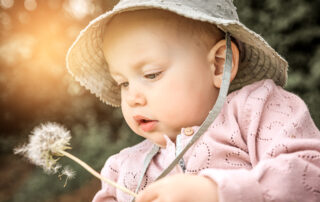 Close up Baby Portrait mit Pusteblume in der Hand, zarte und ruhige Aufnahme.