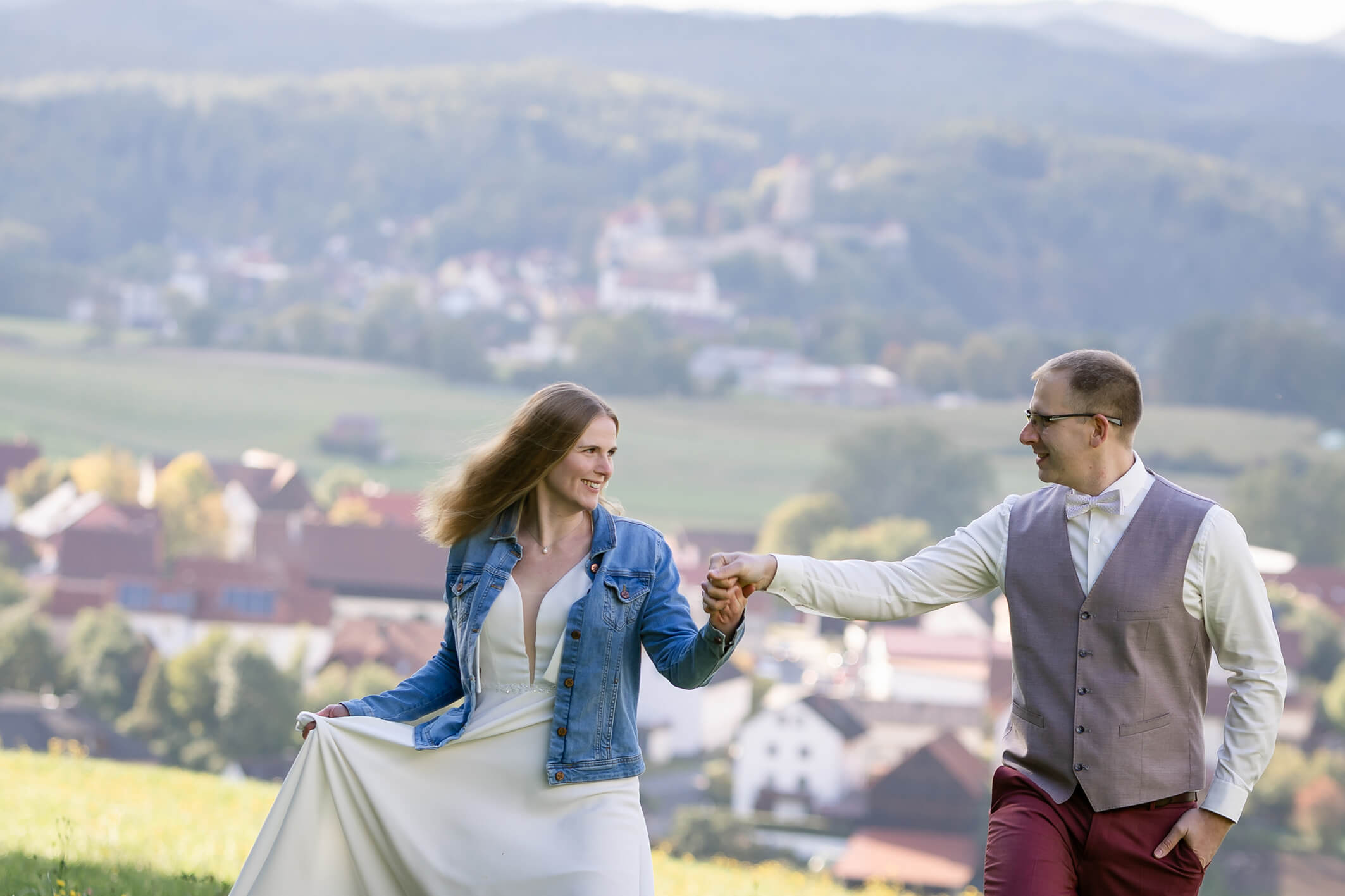Brautpaar steht auf einer Wiese und küsst sich, weicher Hintergrund und ruhige Bildstimmung.