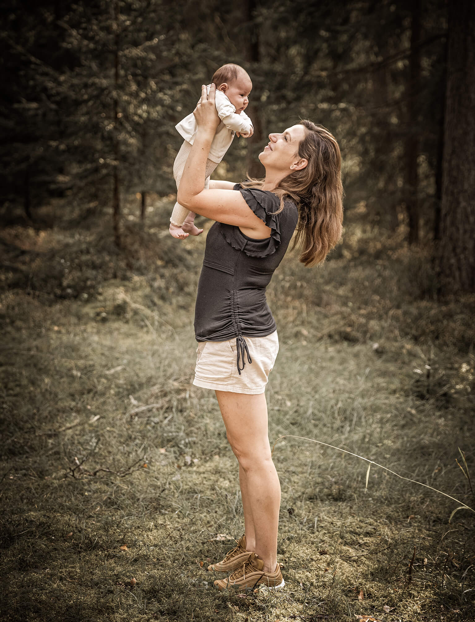 Familienfoto-indernatur-Mutterliebe-doris-dörfler-pegnitz Mutter hebt ihr Baby im Wald nach oben, liebevolles Familienportrait in der Natur.