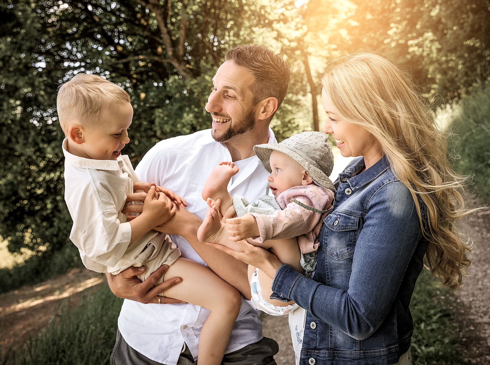 Familyportrait-schlossber-natur-onlaction-dörfler-doris-lichtblick Familie mit zwei Kindern in Bewegung, der Bruder spielt mit dem Baby, alle lachen.