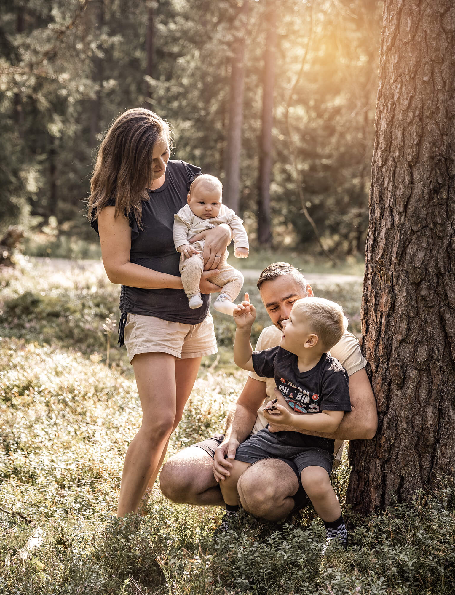 Veldnsteinerforst-familienfotos-doris-dörfler-pegnitz-weiden Familie im Wald, Mama hält ihr Baby im Arm, Papa hat den Sohn auf dem Schoß, warmes Licht von oben.