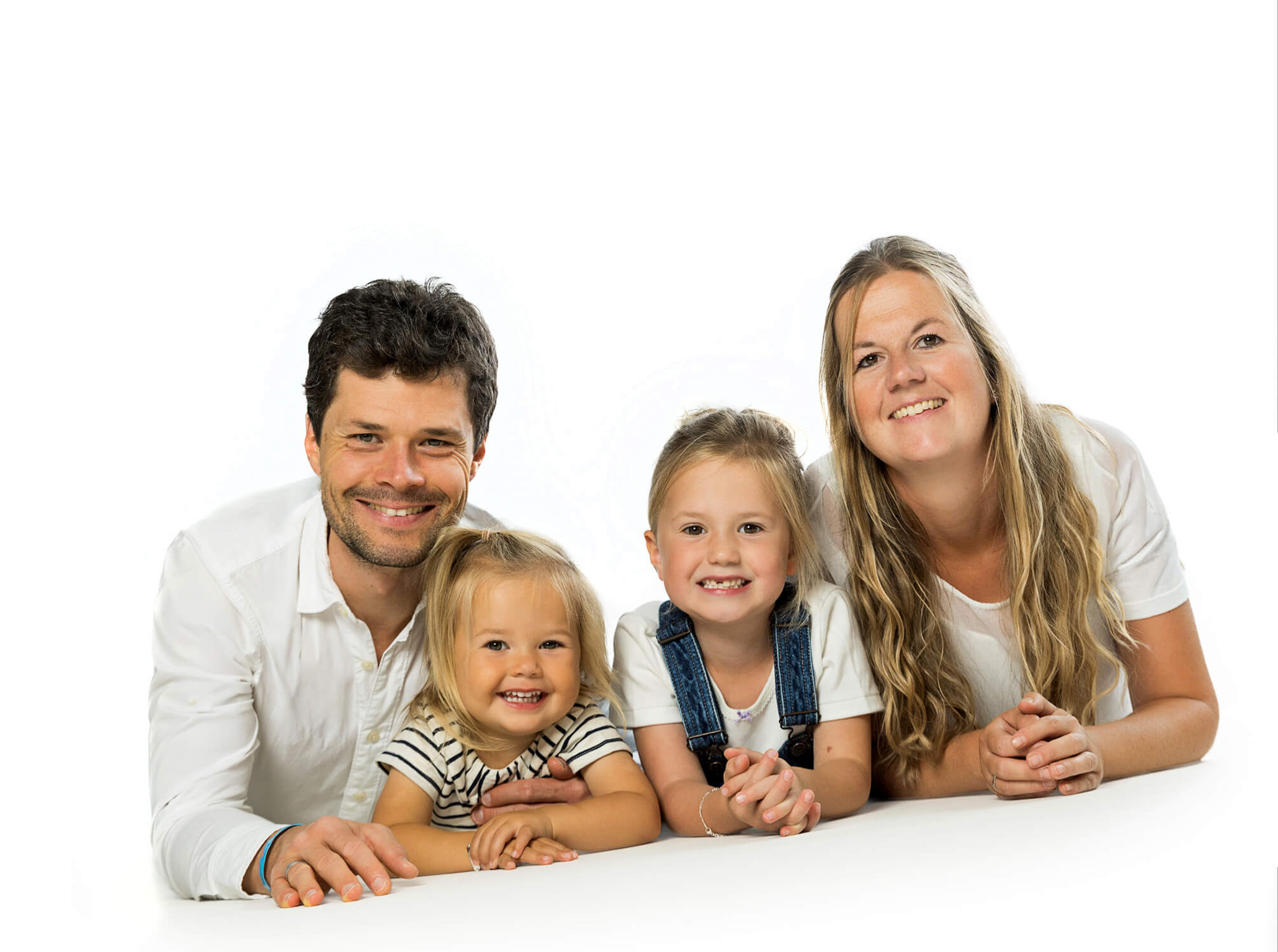 familienfoto-geschwisterportrait-doris-dörfler-fotostudio-lichtblick Familie im Fotostudio auf weißem Hintergrund, alle liegen auf dem Bauch und lachen in die Kamera.
