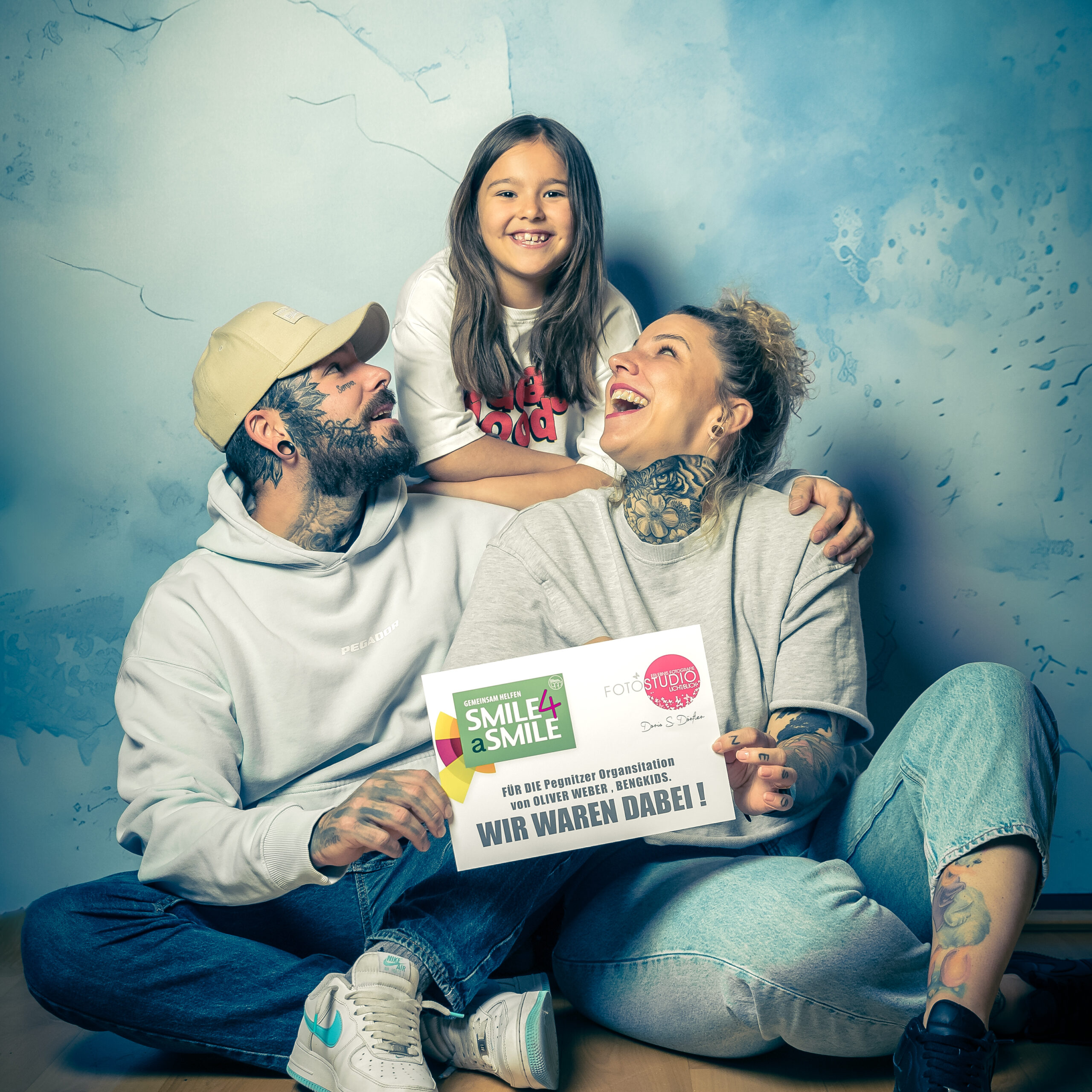 Familie sitzt auf dem Boden sie halten ein Schild in der Hand auf dem steht Spendenaktion wir waren dabei