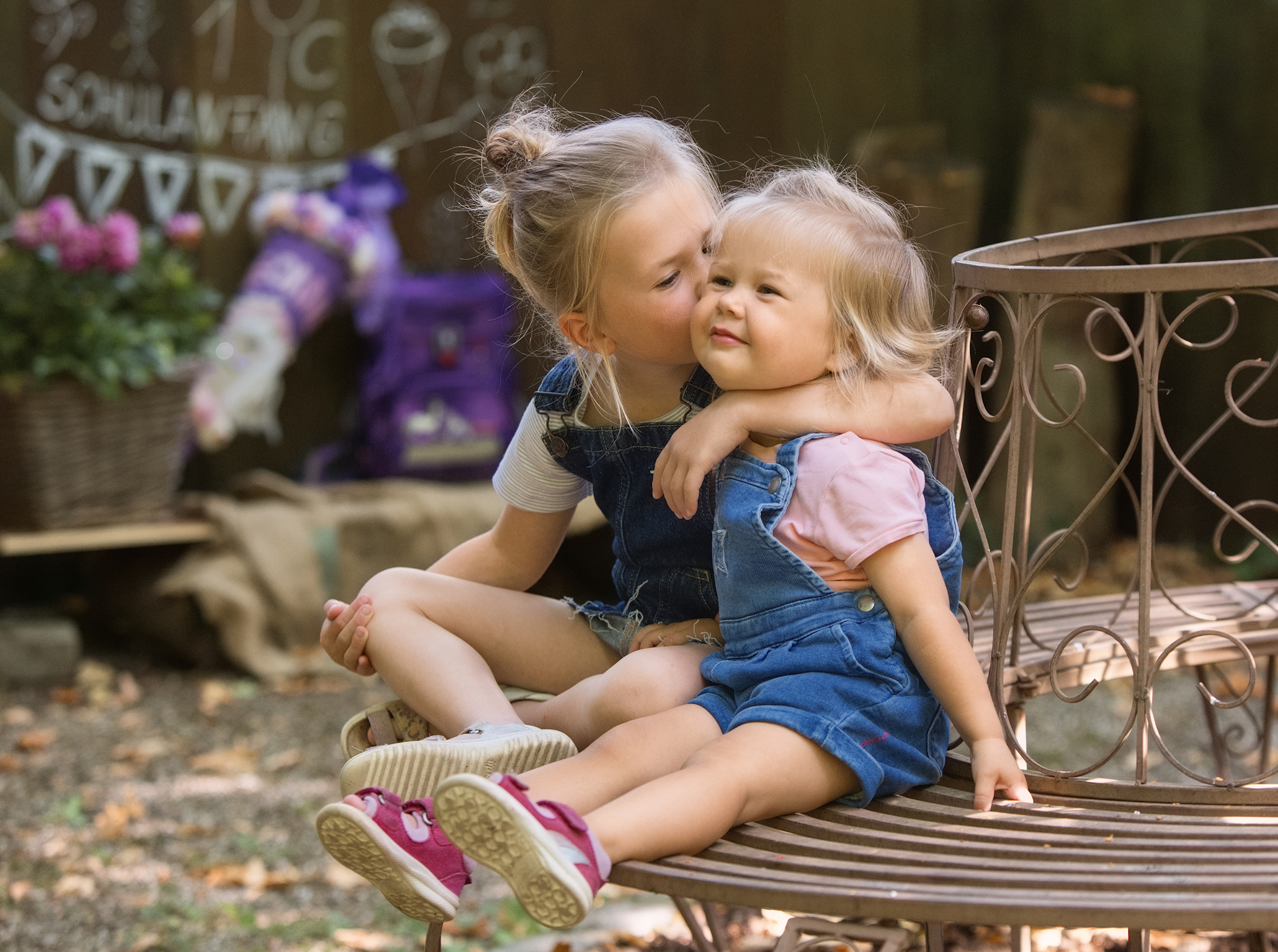 Schulanfangfotos-geschwisterfoto-Doris-Dörfler-endlich-schulkind-Fotostudio-Lichtblick-Pegnitz Geschwisterfoto zweier Mädchne die groß Schwester gibt der kleinen einen Schmatz auf die Backe